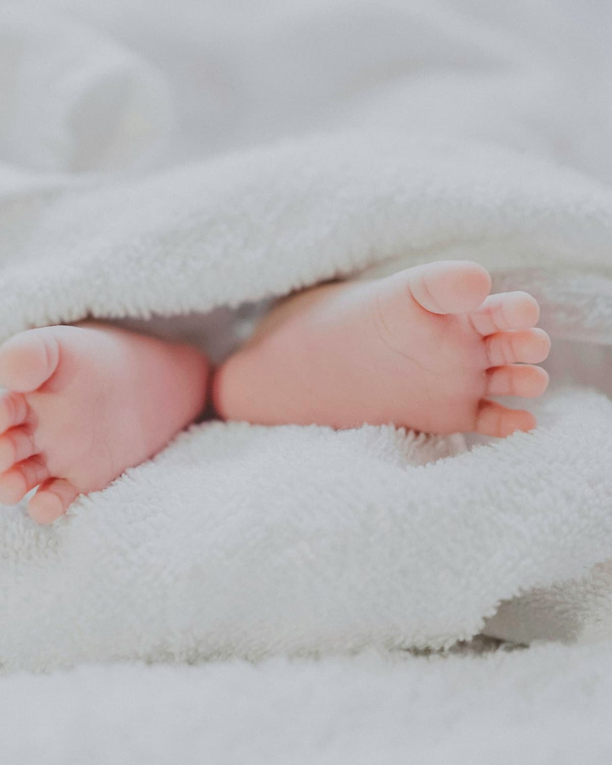 Newborn wrapped in a soft blanket held by a parent